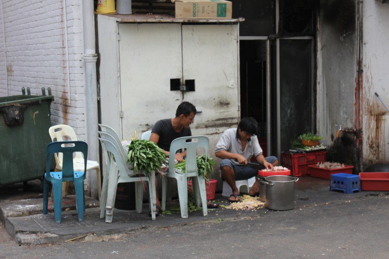 Can you see what the guy on the left is up to? He's chopping the nails off chicken feet (I think). That's what the pile on the ground is.